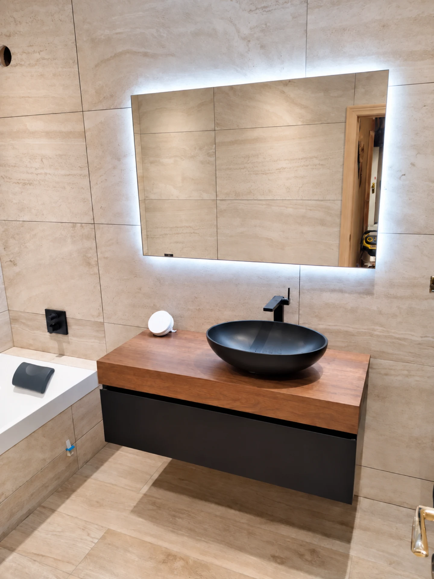 Meuble vasque en bois, vasque noire et miroir LED dans une salle de bain rénovée